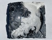 Top-down photo of the polished quartz crystal ashtray with visible symbolic etchings and marbled black and white texture.