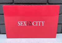 Top view of red Sex in the City gift box with logo on front.