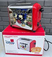 Photo of toaster on original box showing Mickey Mouse design and product front.
