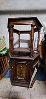 Wooden octagon end table with cabinet base and open door shown in storage.