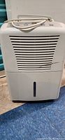 Front view of white portable dehumidifier showing vented panel and water tank