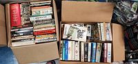 Four boxes filled with various books including vintage editions and contemporary novels.