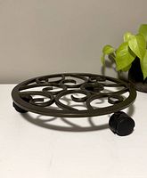 Photo of round metal rolling plant stand with decorative scroll design and caster wheels, empty.