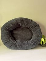 Overall view of an oval-shaped, gray plush dog bed with raised cushion sides.