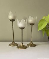 Front view showing all three brass and glass tulip candle holders of varying heights with frosted glass tulip-shaped holders and faux white tea lights inside.