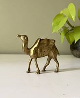 Photo of vintage brass camel figurine, side view showing saddle details and curved neck.