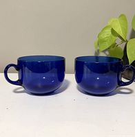 Front side view of two cobalt blue glass mugs placed side by side with no visible damage.