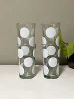 Front view showing stacked pairs of clear glass tumblers with white polka dot design.