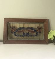 Front view of vintage stained glass window with bow tie design in wooden frame on white surface.