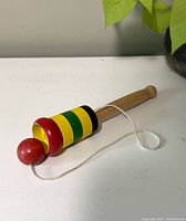 Side view photo of the vintage wooden cup and ball toy with red ball and striped painted cup