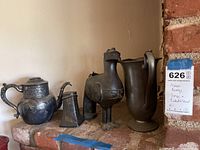 Overall photo of the lot showing the bronze horse figurine in the center flanked by pewter pitchers and jugs on a stone mantel.