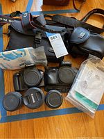 Overview of two camera bodies, three lenses, camera bag, small pouch, straps, and caps