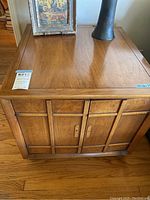 Front view of the wooden Drexel end table showing the paneled cabinet doors and scratches on the surface.