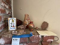 Overall lot view of southwest pottery jars, decorative items on brick corner shelf