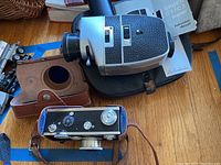 Bauer C1/C2 Super movie camera with instruction manual and black leather case alongside Argus camera in brown leather case