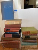 Stack of vintage books including 'Candide' and 'Hawaii' by James A. Michener, assorted hardcovers.