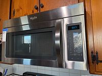 Front view of Whirlpool microwave showing stainless steel door with window and digital control panel displaying time 5:57.