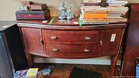 Full front view of wooden buffet cabinet showing drawers, side doors, and items placed on top (contents not included).