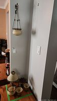 Photo showing the hanging candle holder and tea light lamp suspended from the wall, along with three table candle holders placed on a wooden surface.