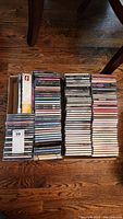 Two boxes filled with various CDs and DVDs arranged on the floor.