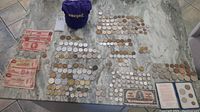 Overview of many coins and paper currency laid on a tiled floor including various vintages and countries