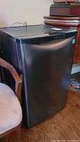Angled front view of compact black Danby mini fridge.