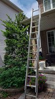 Full view of a lightweight aluminum extension ladder leaning against a porch, about 24 feet long.