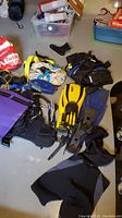 Photo showing scuba fins, gloves, diving boots, weights, dry bag, and some small accessories scattered on floor.