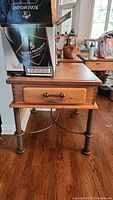 Full view of the wooden side table showing the drawer front, handle, and metal legs with boxes placed on top (not included).