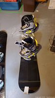 Snowboard with boots and bindings arranged on floor showing overall setup.