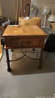 Front and side angle view of wood table with metal legs and single drawer showing condition and design.