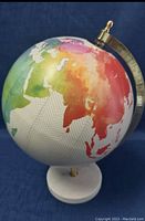 Front view showing colorful artistic rendering of continents on the globe and marble base.
