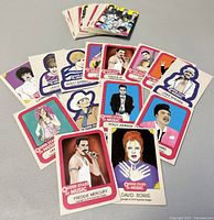 Spread of queer music stars collector cards including Freddie Mercury, David Bowie, Janis Joplin and others