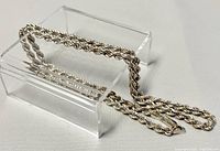 Full view of silver rope chain necklace displayed on clear stand, showing chain texture and length.