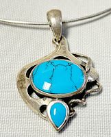 Close-up of turquoise pendant with oval and teardrop-shaped stones set in sterling silver openwork frame