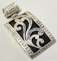 Front top view of the silver pendant showing scrollwork and onyx