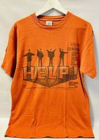 Front view of orange Beatles 'HELP!' T-shirt showing movie poster styled graphic with silhouettes and text.