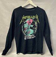 Front view of black long sleeve Metallica T-shirt, showing colorful skull graphic and text on front.
