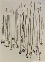 Full view of all assorted vintage costume necklaces with various pendants displayed laid flat.