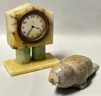 Desk clock and soapstone walrus carving side by side on light background