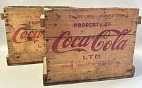 Two vintage Coca-Cola wooden crates stacked showing the red logos and text on exterior sides.