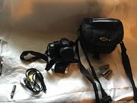 Full lot showing camera with strap, JVC camera bag, battery charger, AV cable, and AA batteries.