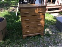Front view of oak dresser standing outdoors showing four drawers with wooden handles.