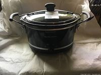 Front view of Hamilton Beach small Crock Pot slow cooker with glass lid and black handles.