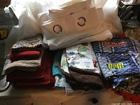 Photo of stacked household linens including white curtains, child-themed sheets, and various colored towels.