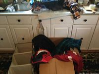 Boxes containing boys winter coats in red, black, and blue plaid inside a kitchen setting