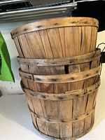 Four stacked vintage wooden bushel baskets showing their size and condition with visible wear and wood grain.