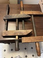 Two antique wooden woodworking clamps placed side by side on a table showing full clamp length and jaws