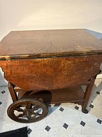 Front view of the closed wooden tea cart showing drop-leaf top and wood grain.