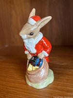 Front view showing bunny in Santa outfit holding sack of toys.